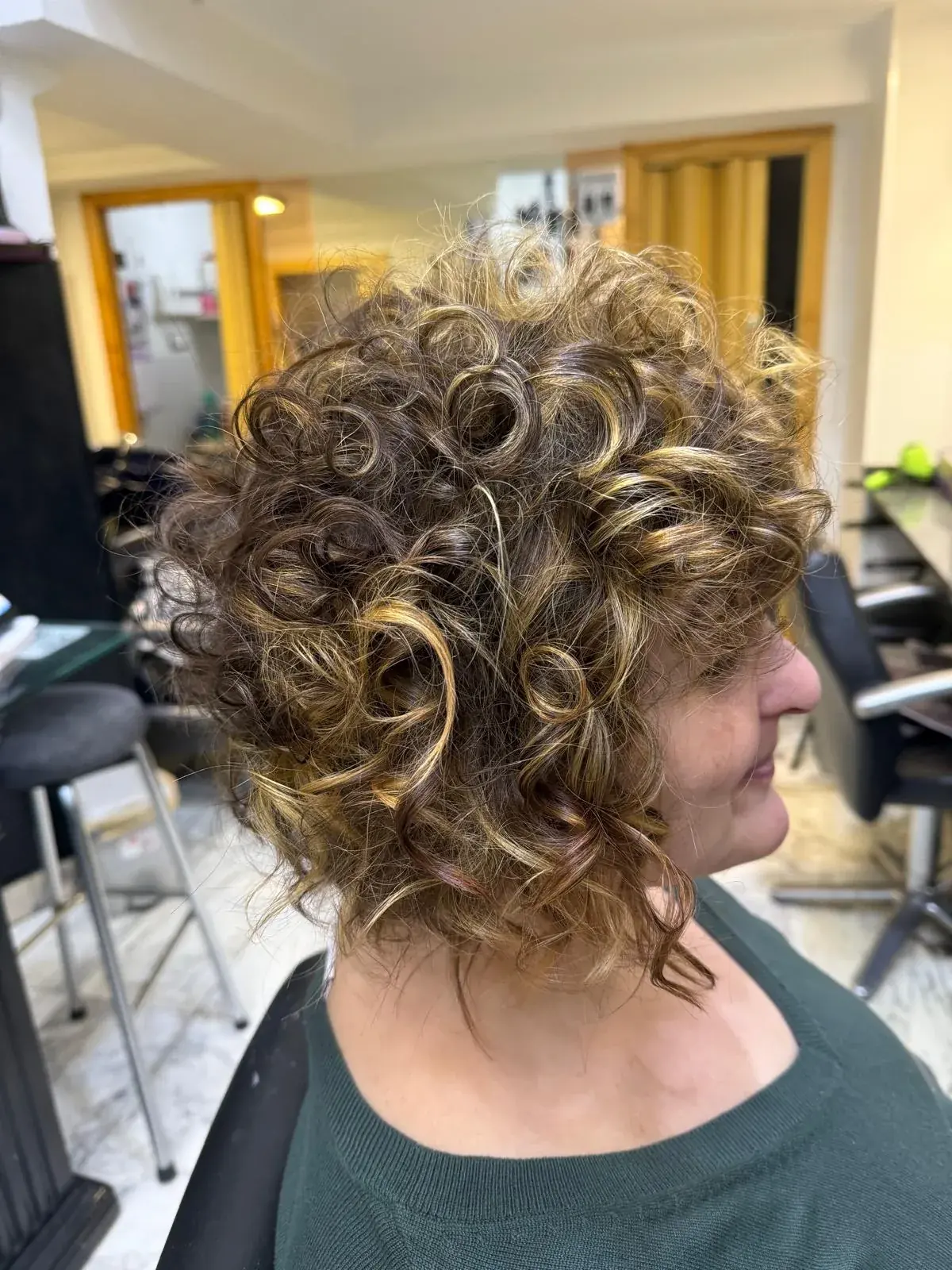 Corte de cabello rizado corto con mechas y brillo realizado en Zache